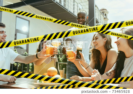 Group of friends clinking glasses of beer at bar with bounding tapes Lockdown, Coronavirus, Quarantine, Warning - closing bars and nightclubs during pandemic 73465928