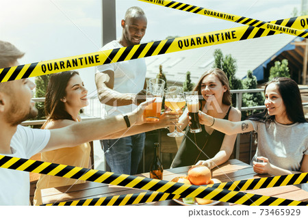 Group of friends clinking glasses of beer at bar with bounding tapes Lockdown, Coronavirus, Quarantine, Warning - closing bars and nightclubs during pandemic Group of friends clinking glasses of beer at bar with bounding tapes Lockdown, Coronavirus, Quarantine, Warning - closing bars and nightclubs during pandemic 73465929