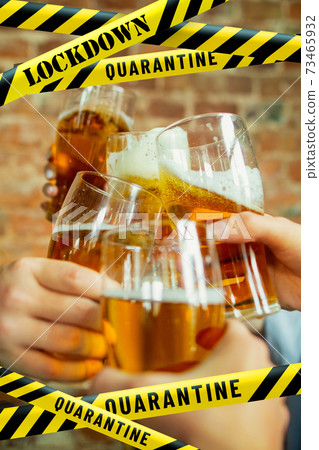 Close up hands clinking glasses of beer at bar with bounding tapes Lockdown, Coronavirus, Quarantine, Warning - closing bars and nightclubs during pandemic Close up hands clinking glasses of beer at bar with bounding tapes Lockdown, Coronavirus, Quarantine, Warning - closing bars and nightclubs during pandemic 73465932