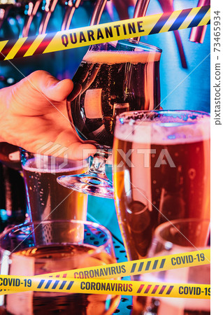 Hand of bartender pouring a beer in tap with bounding tapes Lockdown, Coronavirus, Quarantine, Warning - closing bars and nightclubs during pandemic 73465934