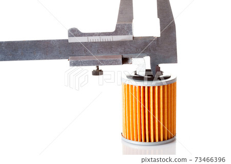 Measurements of the internal size and diameter of the car filter caliper, isolated spare part paper orange filter and caliper on a white background. 73466396
