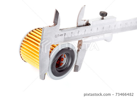 Calibration with a caliper of the outer size of a round paper car filter orange color, the process of measuring the details of the tool isolated on a white background. 73466482