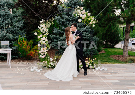 wedding ceremony in arch of living flowers.Beautiful newlyweds gently kissing wedding ceremony in arch of living flowers.Beautiful newlyweds gently kissing 73466575