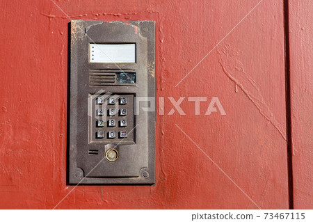 an intercom on metall used door with a keypad for calling close up with copy space. an intercom on metall used door with a keypad for calling close up with copy space. 73467115