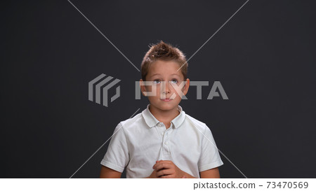Expecting miracle boy in white shirt holding hands together in front of him while looking sideways at upper corner. Isolated on black background Expecting miracle boy in white shirt holding hands together in front of him while looking sideways at upper corner. Isolated on black background 73470569