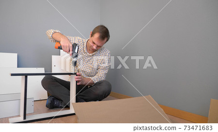 handsome man collects furniture at home in the room. copy space handsome man collects furniture at home in the room. copy space 73471683