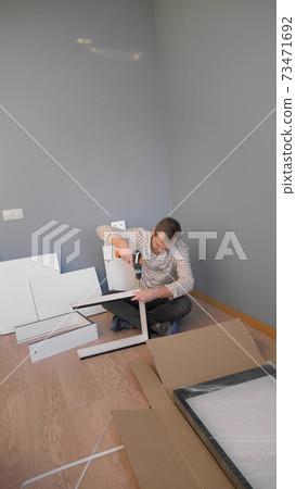 handsome man collects furniture at home in the room. copy space 73471692