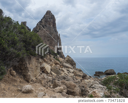 View of Pedra Longa, limestone rock pillar at coast Gulf of Orosei, beginning of the famous and difficult hiking climbing trail Selvaggio blu, wild blue, Sardinia, Italy 73471828