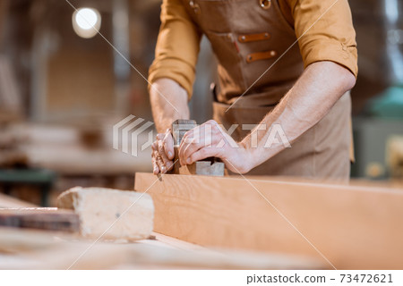 Carpenter working with a wood in the workshop Carpenter working with a wood in the workshop 73472621