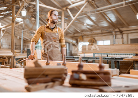 Portrait of a handsome carpenter at the joiner's shop 73472693