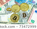 Silver and gold bitcoin coins on paper euro and dollar banknotes. Modern virtual currency 73472999
