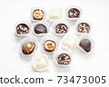 Different chocolate pralines. Belgian pralines of different shapes in paper baskets 73473005