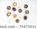 Different chocolate pralines. Belgian pralines of different shapes in paper baskets 73473031