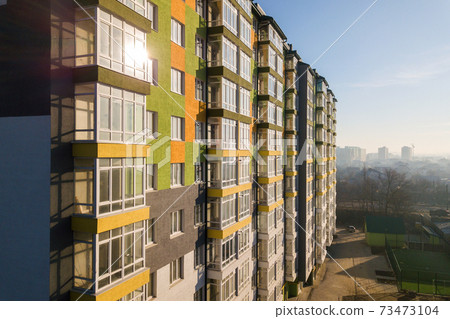 Aerial view of a tall residential apartment building with many windows and balconies. 73473104