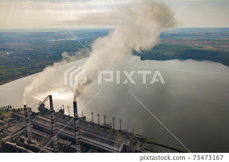 Aerial view of high chimney pipes with grey smoke from coal power plant. Production of electricity with fossil fuel. Aerial view of high chimney pipes with grey smoke from coal power plant. Production of electricity with fossil fuel. 73473167
