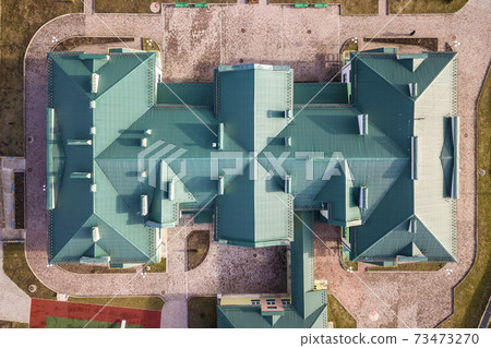 Top aerial view of building green shingle tiled roof with complex configuration construction. Abstract background, geometrical pattern. 73473270