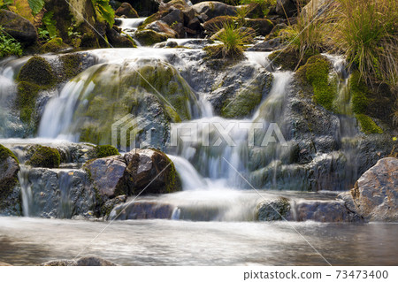 Small Waterfall in park with beautifull smooth water. Little waterfall in mountain forest with silky foaming water. Small Waterfall in park with beautifull smooth water. Little waterfall in mountain forest with silky foaming water. 73473400