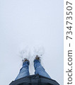 Feet in boots under fresh snow 73473507