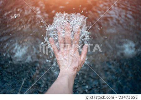 Man's hand touching a natural water source Man's hand touching a natural water source 73473653