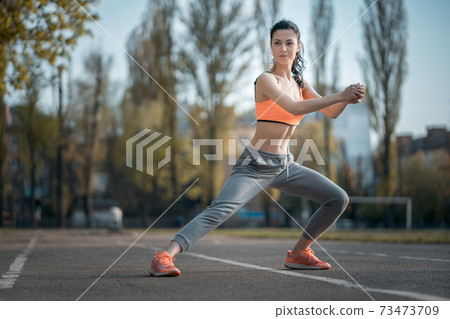 attractive brunette woman warm up and stretching in park at sunshine attractive brunette woman warm up and stretching in park at sunshine 73473709