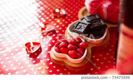 Chocolates and sweets on heart-shaped plates. Festive table setting for date Chocolates and sweets on heart-shaped plates. Festive table setting for date 73473899