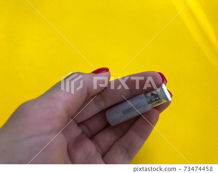 Hand of a doctor wearing protecting glove holding a glass test tube with blood sample and a Covid 19 sign on it 73474458