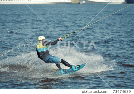 Young man riding wakeboard on a summer lake 73474689