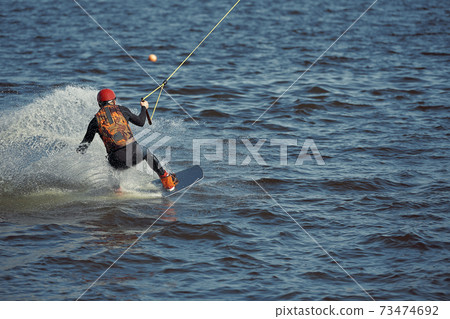 Young man riding wakeboard on a summer lake Young man riding wakeboard on a summer lake 73474692