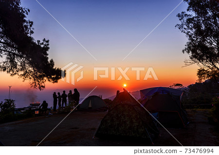 Silhouette tourist group standing on the top of mountain looking to sunrise. 73476994