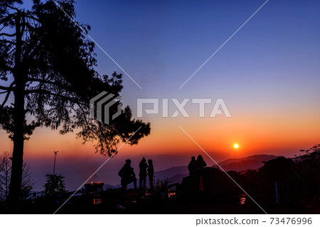 Silhouette tourist group standing on the top of mountain looking to sunrise. Silhouette tourist group standing on the top of mountain looking to sunrise. 73476996
