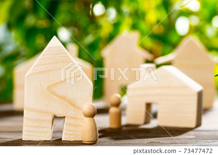Wooden toy house and wooden family on foliage background Wooden toy house and wooden family on foliage background 73477472