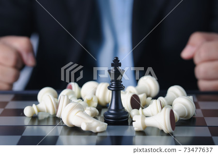 Businessman finger hands control chess king to success position on competition business game with falling enemy chess, meaning of planning and strategy decision and achievement goal concept. Businessman finger hands control chess king to success position on competition business game with falling enemy chess, meaning of planning and strategy decision and achievement goal concept. 73477637
