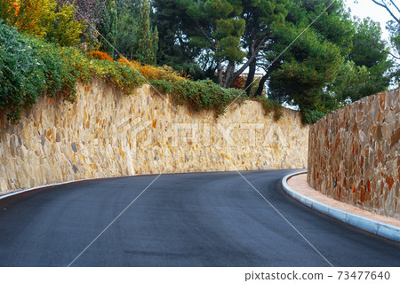Picturesque concrete slope walkway with plants on the sides 73477640