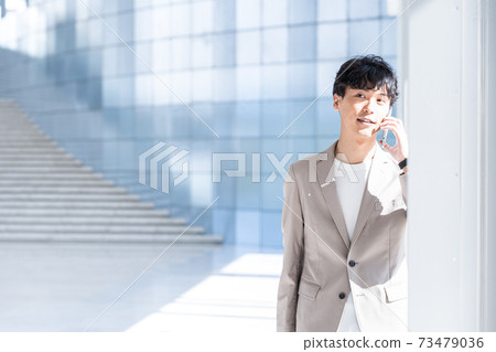 一個年輕的商人在辦公室打電話 73479036
