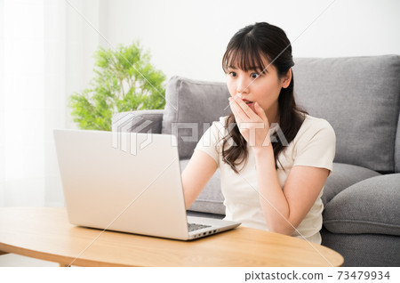A woman who is surprised while looking at the computer screen 73479934