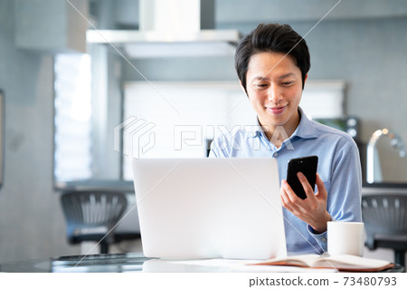 A man who has an online meeting by remote work while looking at a smartphone 73480793