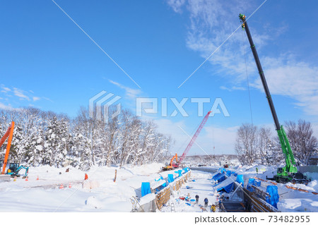 Crane car at winter waterway construction site 73482955