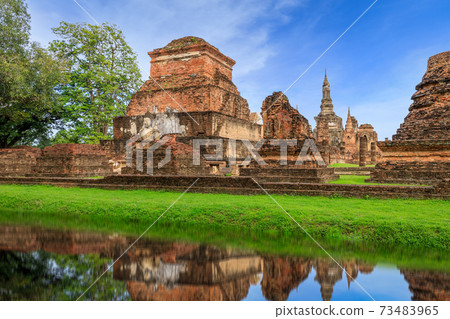 Buddha statue and pagoda Wat Mahathat temple with reflection, Sukhothai Historical Park, Thailand 73483965