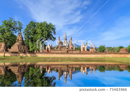 Buddha statue and Pagoda in ruined monastery complex at Wat Mahathat temple with reflection, Sukhothai Historical Park, Thailand 73483966