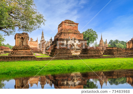 Buddha statue and pagoda Wat Mahathat temple with reflection, Sukhothai Historical Park, Thailand 73483988