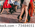 people are dancing outdoors in the park at sunny day. beautiful female feet in dancing shoes in the foreground and background and red skirt 73484031