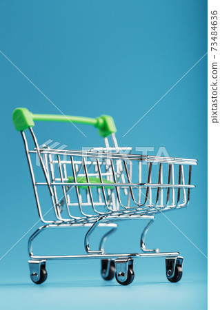 An empty supermarket cart on a blue background. An empty supermarket cart on a blue background. 73484636