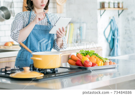 使用片劑的一位主婦在廚房裡 73484886