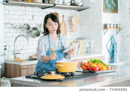 A housewife using a tablet in the kitchen A housewife using a tablet in the kitchen 73484888