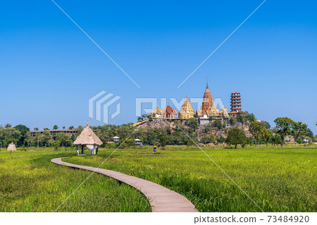 Tiger Cave Temple (Wat Tham Suea) in Kanchanaburi, Thailand with green rice field in sunny day 73484920
