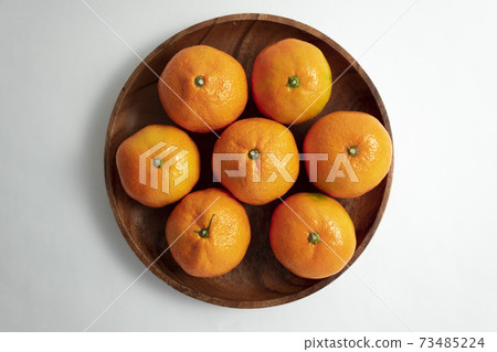 Tangerines on a wooden bowl 73485224