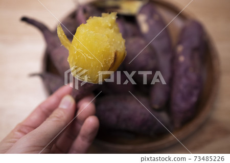 An image of a freshly baked winter snack with roasted sweet potatoes in one hand An image of a freshly baked winter snack with roasted sweet potatoes in one hand 73485226