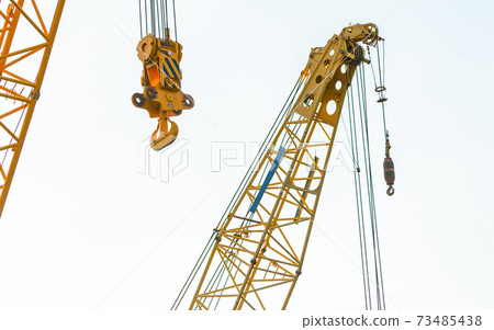 Crawler crane isolated on white background. Real estate industry. Yellow crawler crane use reel lift up equipment in construction site. Crane for rent. Crane dealership for construction business. 73485438