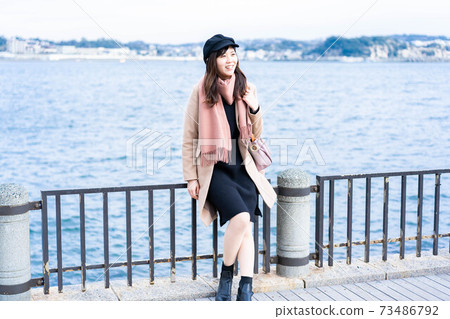 A woman sitting on a sea fence and taking a break while traveling 73486792