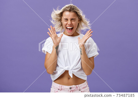 My positive emotions lifting me up. Portrait of happy emotive gorgeous woman with fair hair and tanned skin dancing and jumping on windy weather screaming with closed eyes from happiness shaking hands My positive emotions lifting me up. Portrait of happy emotive gorgeous woman with fair hair and tanned skin dancing and jumping on windy weather screaming with closed eyes from happiness shaking hands 73487185